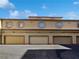 Three-car garage with tan doors and parking area at 5960 Palmilla St # 3, North Las Vegas, NV 89031