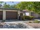 Attractive condo exterior with a brown garage door and mature landscaping at 2477 Vallarta Cir, Las Vegas, NV 89121