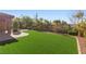 Expansive artificial turf backyard featuring mature landscaping, a stone patio, and perimeter fencing at 2717 Mona Lisa St, Henderson, NV 89044