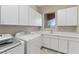 Bright laundry room with white cabinets, sink, and appliances at 2717 Mona Lisa St, Henderson, NV 89044