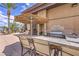 Outdoor kitchen area featuring a built-in grill, bar seating, and a shaded dining space for entertaining at 2717 Mona Lisa St, Henderson, NV 89044