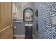 Stylish powder room featuring unique wallpaper, a pedestal sink, a decorative mirror, and a wood-paneled door at 3173 Lido Isle Ct, Las Vegas, NV 89117