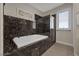 Bathroom featuring black marble walls around the tub, glass shower and white walls at 3173 Lido Isle Ct, Las Vegas, NV 89117