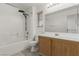 Bathroom features a shower-tub combo, wood cabinets, and a large mirror at 6382 Lonesome Lake St, Las Vegas, NV 89148