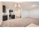 Open-concept living room featuring plush carpeting, modern light fixtures, and seamless flow into the kitchen at 762 Star Estates Ave, North Las Vegas, NV 89086