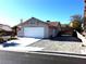 Front view of a house with a white garage door and gravel driveway at 3139 Ocotillo Dr, Laughlin, NV 89029