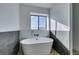 Relaxing bathroom with freestanding tub, marble accents, and dark tile at 3367 Vema Dr, Las Vegas, NV 89121