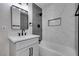 Modern bathroom with marble tile, white vanity, and black fixtures at 4962 E Baltimore Ave, Las Vegas, NV 89104