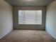 Simple bedroom with neutral walls and carpet, featuring a large window with blinds at 5710 E Tropicana Ave # 2148, Las Vegas, NV 89122