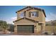 Two-story house with tan siding, green garage door, and landscaping at 9998 Ullom Dr # 16, Las Vegas, NV 89141