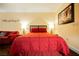 Cozy bedroom with a red comforter and modern lamps at 30 Strada Di Villaggio # 115, Henderson, NV 89011