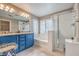 Elegant bathroom with blue vanity, granite countertop, soaking tub, and walk-in shower at 7234 Regent Pond St, Las Vegas, NV 89166