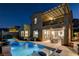 Stunning nighttime view of a home with a sparkling pool, patio furniture, and pergola at 1968 Regal Bluff Dr, Henderson, NV 89052