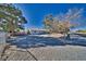 House with gravel driveway and mature trees on a sunny day at 561 Jarvis Rd, Pahrump, NV 89060