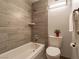 Tiled bathtub and toilet beneath modern lighting and a towel rack in the bathroom at 725 N Royal Crest Cir # 215, Las Vegas, NV 89169