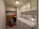 A well-lit laundry room equipped with a washer and dryer, cabinets, and shelving at 725 N Royal Crest Cir # 215, Las Vegas, NV 89169
