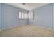 Corner bedroom with light blue walls, neutral carpeting, plantation shutters, and bright natural light at 29 Desert Highlands Dr, Henderson, NV 89052