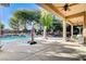 Spacious covered patio with ceiling fans overlooking a beautiful pool and garden at 29 Desert Highlands Dr, Henderson, NV 89052