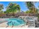 Sparkling pool and spa with rock waterfall feature in a private backyard at 29 Desert Highlands Dr, Henderson, NV 89052