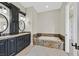 Bathroom with granite countertops, dual sinks, dark cabinets, and a soaking tub at 5790 Aspen Falls Cir, Las Vegas, NV 89149