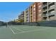 Tennis court with well maintained green surface and black net surrounded by tall condos at 26 E Serene Ave # 124, Las Vegas, NV 89123