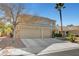 Two-story house with a beige exterior, two-car garage, and desert landscaping at 2875 Skowhegan Dr, Henderson, NV 89074