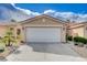 Beige home featuring a two-car garage, rock landscaping and mature trees at 5201 Progresso St, Las Vegas, NV 89135