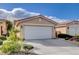 Beige home featuring a two-car garage, rock landscaping and mature trees at 5201 Progresso St, Las Vegas, NV 89135