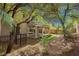 Home's treed backyard with covered patio, rock landscaping, and privacy fencing at 561 Tecate Valley St, Las Vegas, NV 89138