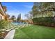 Serene backyard featuring a stunning pool area, lush green lawn, and mature trees, providing a private outdoor retreat at 10923 Willow Heights Dr, Las Vegas, NV 89135