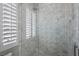 Luxurious bathroom featuring a glass shower with marble tile, a rainfall showerhead, and stylish white shutters at 10923 Willow Heights Dr, Las Vegas, NV 89135