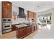 Open-concept kitchen featuring stainless steel appliances, range hood, eat-in island and backyard views at 10923 Willow Heights Dr, Las Vegas, NV 89135