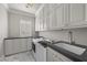 Well-organized laundry room with white cabinetry, gray countertops, modern appliances, and herringbone floors at 10923 Willow Heights Dr, Las Vegas, NV 89135