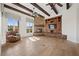 Cozy living room featuring a stone fireplace, wood beams, a comfortable armchair, and natural lighting at 10923 Willow Heights Dr, Las Vegas, NV 89135