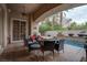 Covered outdoor patio with a seating area, fire pit, and a tranquil water feature in the background at 36 Avenida Fiori, Henderson, NV 89011
