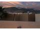 Gorgeous backyard view with string lights on the back wall against a colorful sunset at 9331 Hilgard Ave, Las Vegas, NV 89178