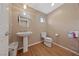 Well-lit bathroom with a pedestal sink, round mirror and wood-look flooring at 9331 Hilgard Ave, Las Vegas, NV 89178