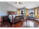 Bright main bedroom with wood flooring, a ceiling fan, and large windows with yellow curtains at 6112 Browning Way, Las Vegas, NV 89130