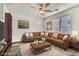 Virtually staged living room with leather sectional sofa and a large window at 7716 Gallego Plains Dr, Las Vegas, NV 89113