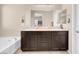 Double vanity bathroom with dark brown cabinets and a soaking tub at 7906 Woolly St, Las Vegas, NV 89149