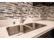 Modern kitchen sink with a stylish faucet, double basin, bright white countertops, and beautiful backsplash at 1321 Cinder Rock Dr # 202, Las Vegas, NV 89128