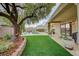 Serene backyard with lush green turf, mature tree, covered patio and sparkling pool beyond at 2009 Fern Hill Ct, Henderson, NV 89052