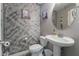 Charming half bathroom featuring a pedestal sink, round mirror, artistic gray textured walls at 10529 Parthenon St, Las Vegas, NV 89183