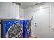 Laundry room with blue washer and dryer, cabinets, and exterior access at 2374 Thayer Ave, Henderson, NV 89074