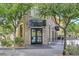 Stone-clad building with a modern grocery store entrance, framed by lush trees and landscaping at 43 Strada Loreto, Henderson, NV 89011