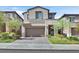 Two-story home featuring a two-car garage, neutral color palette, manicured lawn, and complementary landscaping at 43 Strada Loreto, Henderson, NV 89011