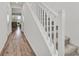 Bright hallway featuring durable wood floors and a staircase with carpeted treads and a white handrail at 43 Strada Loreto, Henderson, NV 89011