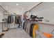 Spacious walk-in closet with ample storage, wooden rods, shelving, and plush gray carpet at 43 Strada Loreto, Henderson, NV 89011