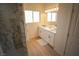 Bright bathroom featuring double sinks, white cabinets, and a large marble shower at 521 Antelope Ave, Pahrump, NV 89060