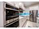 Modern kitchen featuring stainless steel appliances, white cabinets, and a backsplash with a blue accent at 138 Reflection Cove Dr, Henderson, NV 89011